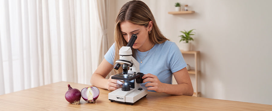 A young woman looking through the eyepiece of a Tomlov fine focus microscope to observe onion cell specimens.