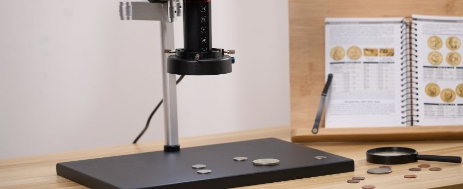 Close-up of the Tomlov Autofocus 4K Digital Microscope lens set up for inspecting coins.