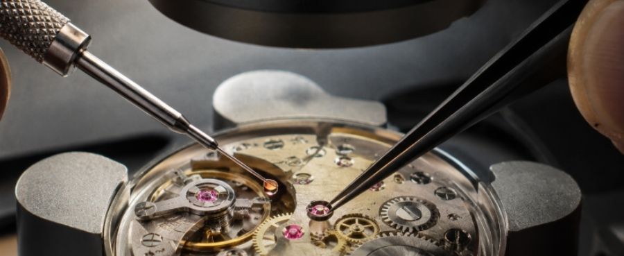 Close-up of a mechanical watch movement being repaired with precision tweezers under a microscope.