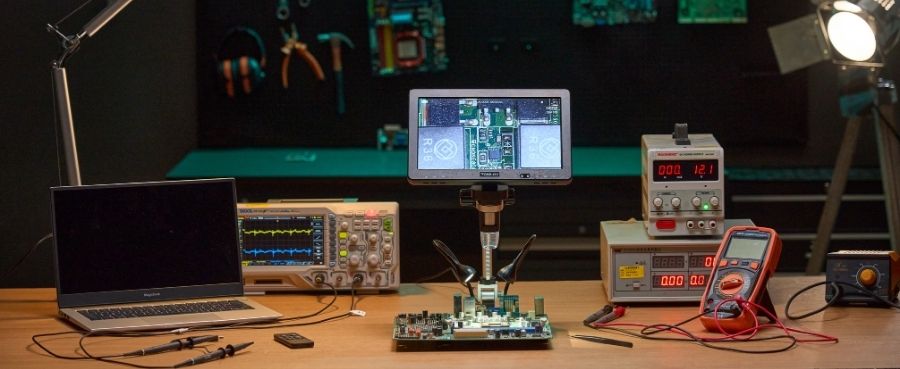 A Tomlov DM9 Max 10.1 HD IPS HDMI Digital Microscope inspecting a circuit board on an electronics testing workbench.